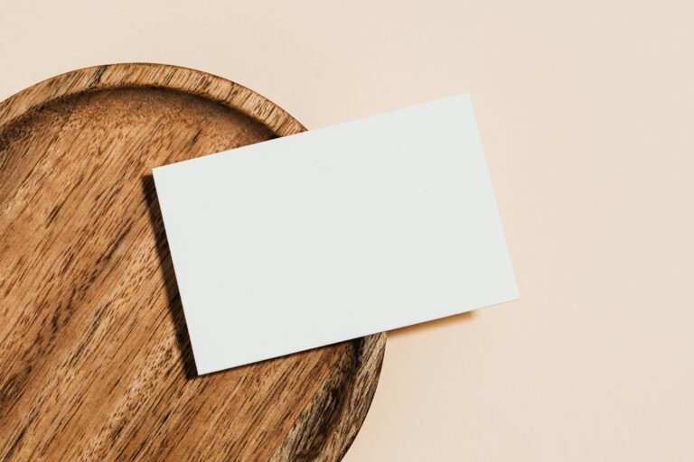Minimalist blank card on a wooden plate placed against a soft pastel background, perfect for mockups.
